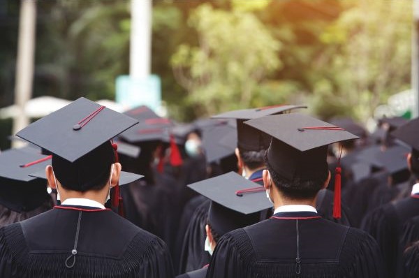 アメリカの大学の卒業式に参加する学生が黒いキャップとガウンを着用している